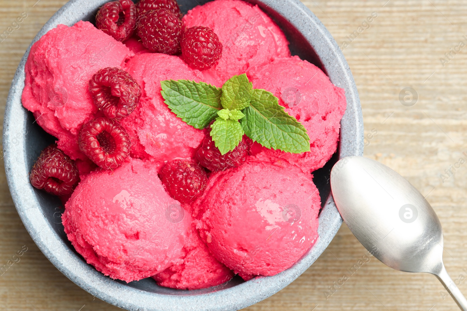 Photo of Delicious raspberry sorbet, fresh berries and mint in bowl served on wooden table, top view