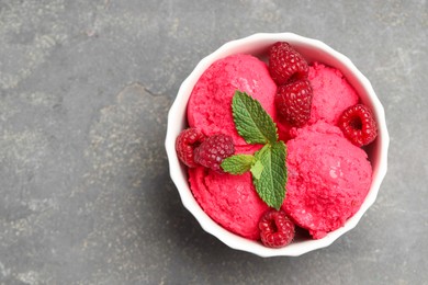 Photo of Delicious raspberry sorbet, fresh berries and mint in bowl on gray textured table, top view. Space for text