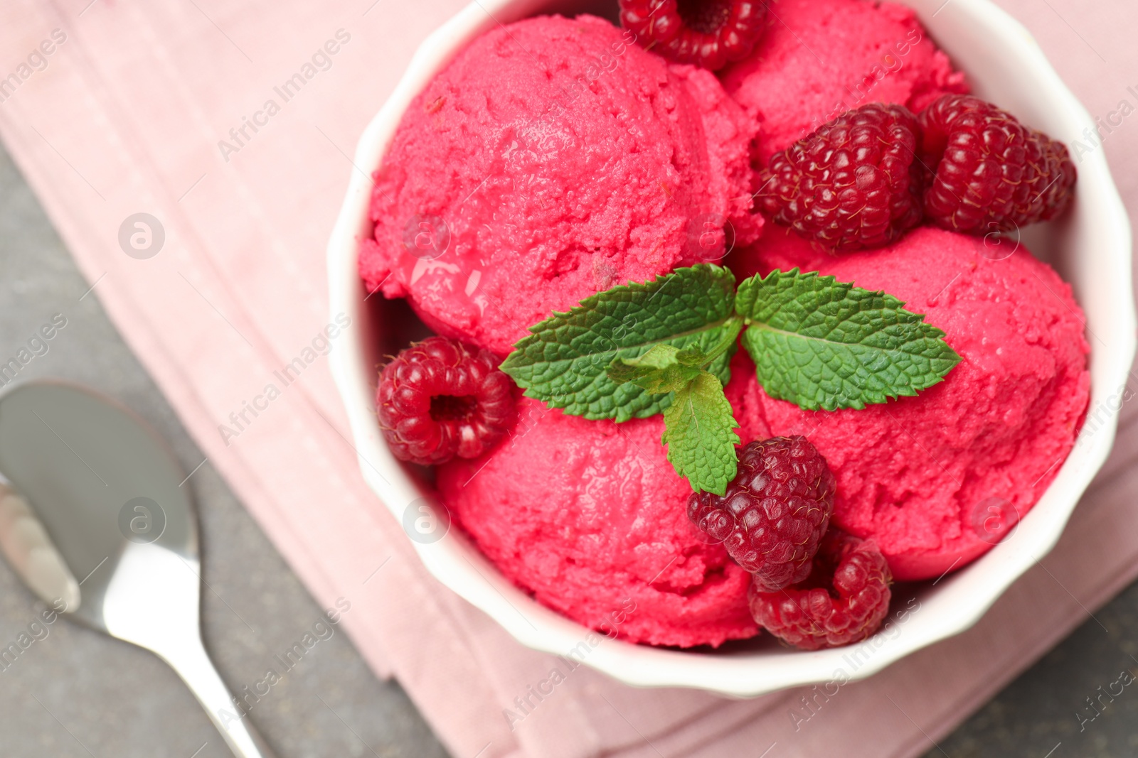 Photo of Delicious raspberry sorbet with fresh berries in bowl and spoon on gray table, flat lay