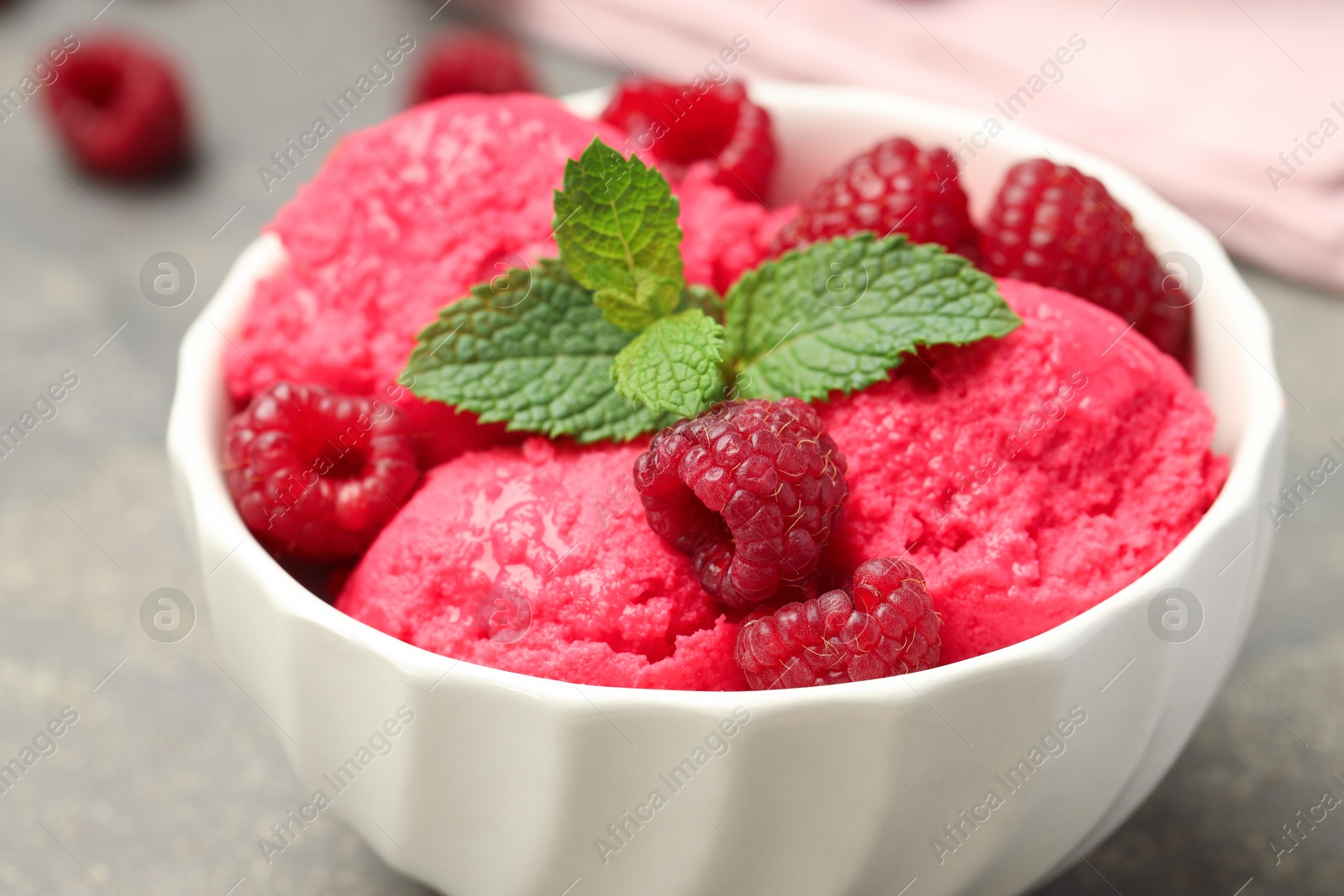 Photo of Delicious raspberry sorbet, fresh berries and mint in bowl on gray table, closeup