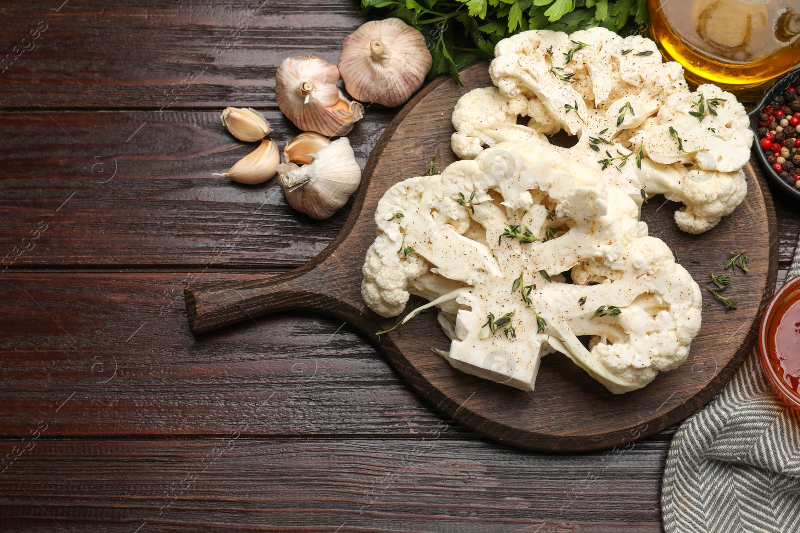 Photo of Uncooked cauliflower steaks, oil and spices on wooden table, flat lay