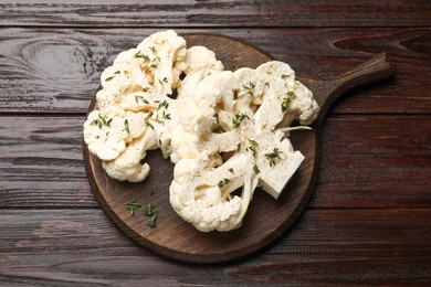 Photo of Uncooked cauliflower steaks with spices on wooden table, top view