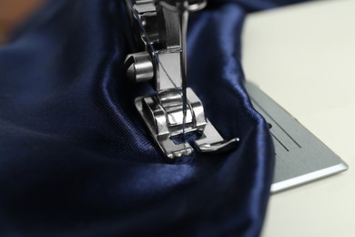 Photo of Sewing machine with blue fabric, closeup view