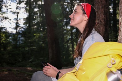 Young hiker with smartphone resting in forest