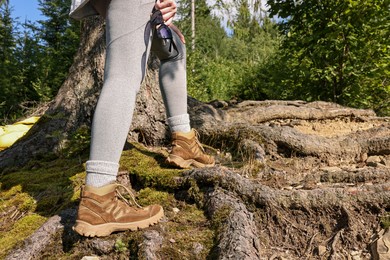 Photo of Young hiker in trekking shoes walking outdoors, closeup