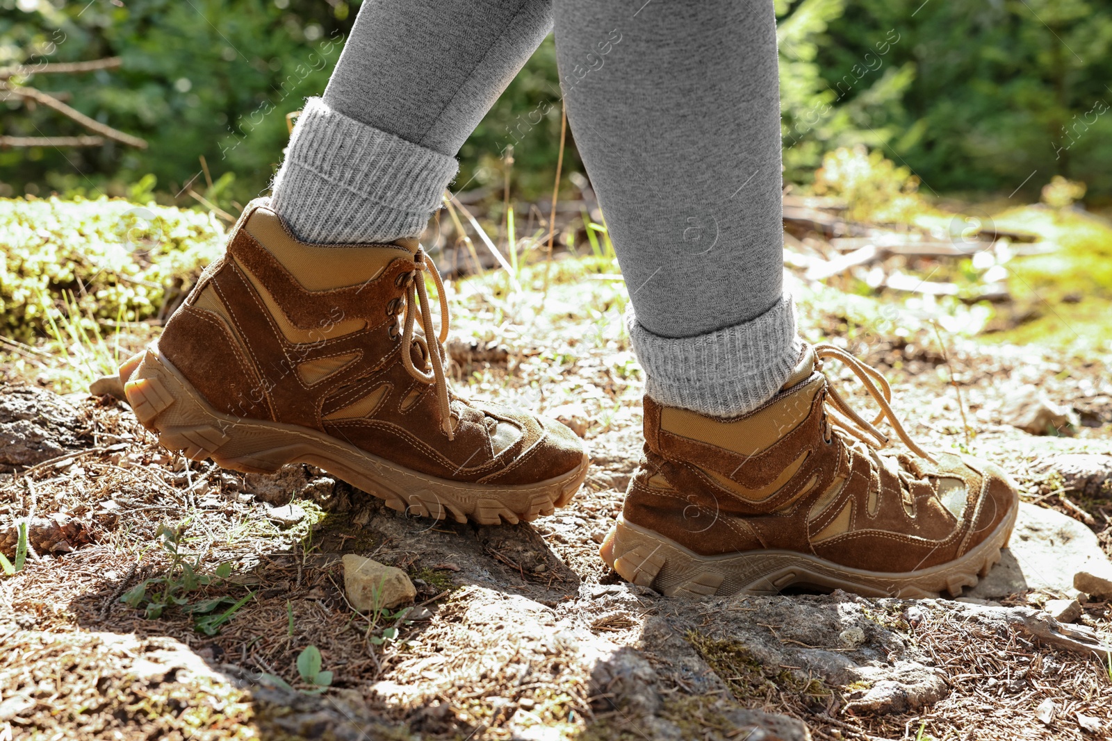 Photo of Young hiker in trekking shoes walking outdoors, closeup