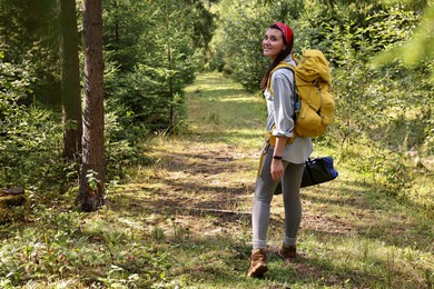 Young hiker with backpack walking in forest