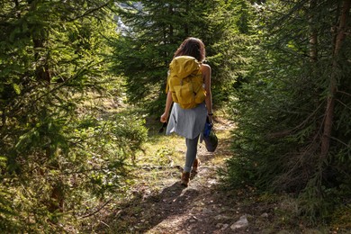 Young hiker with backpack walking in forest