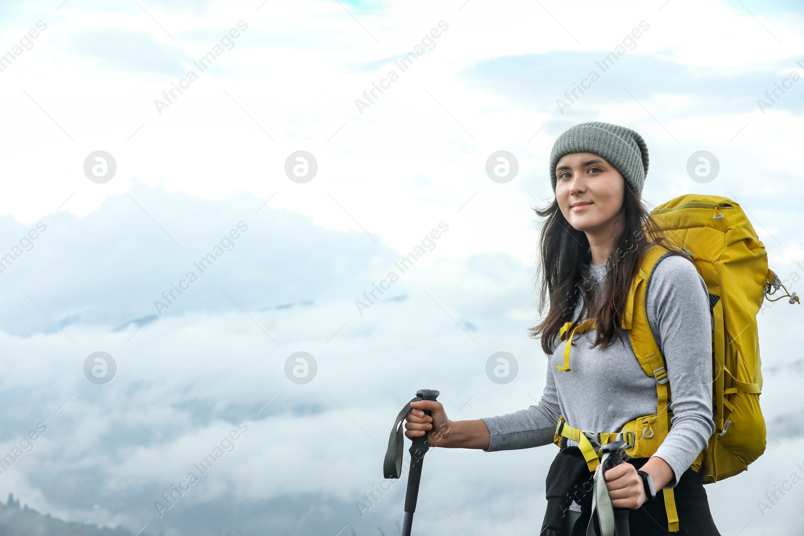 Photo of Young hiker with backpack and trekking poles in mountains, space for text