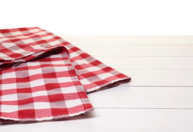 Folded tablecloth with checkered pattern on wooden table against white background