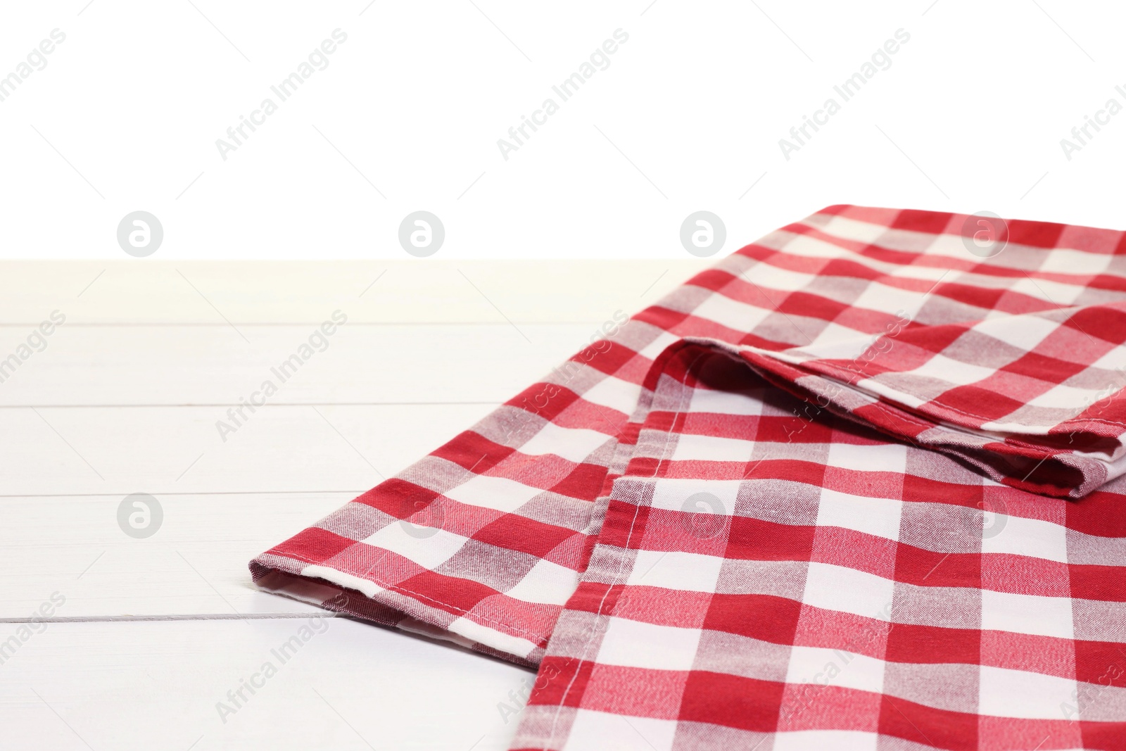 Photo of Folded tablecloth with checkered pattern on wooden table against white background