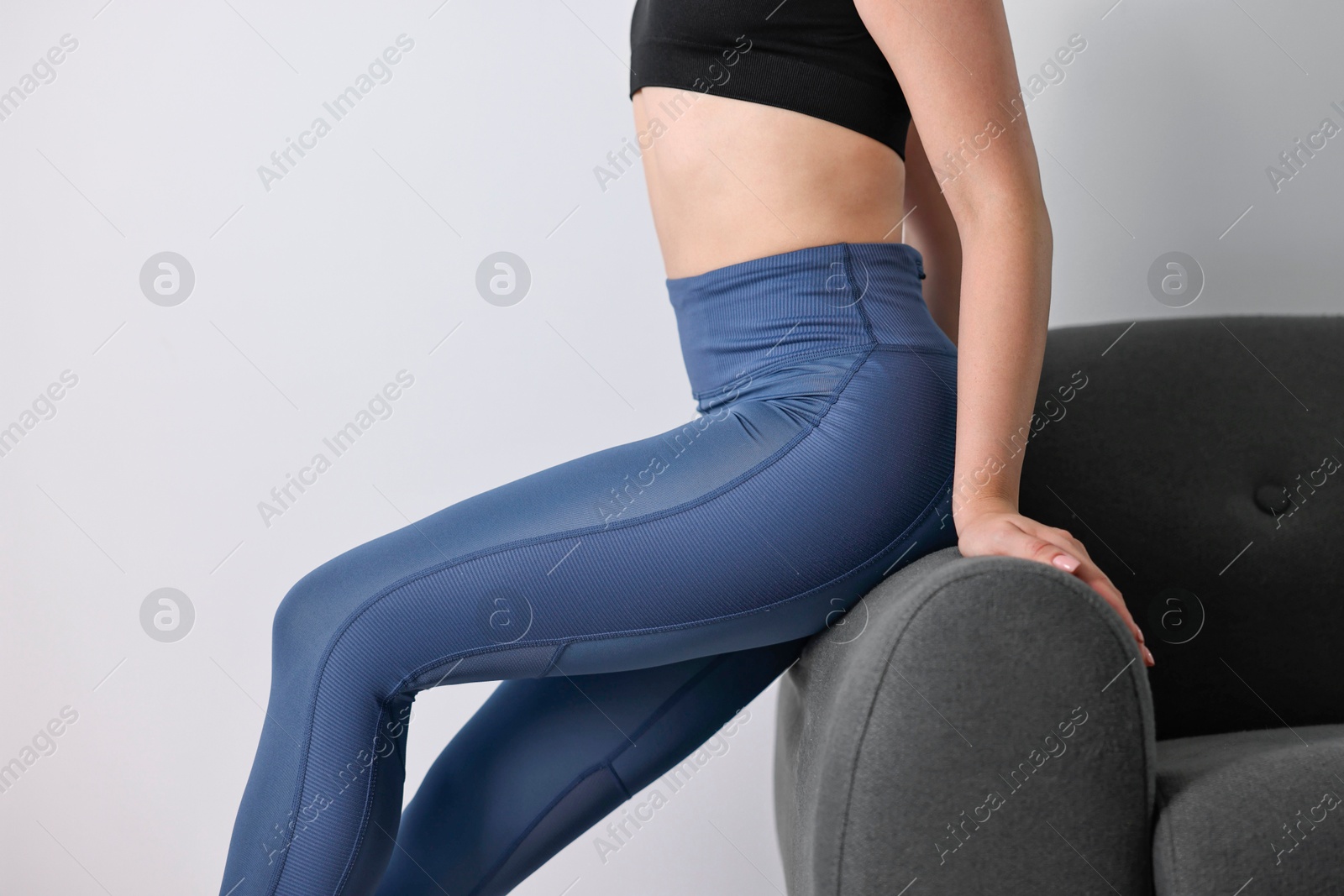 Photo of Woman wearing blue sports leggings on sofa indoors, closeup