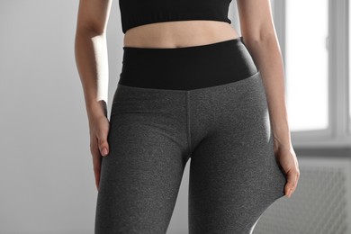 Woman wearing grey sports leggings indoors, closeup