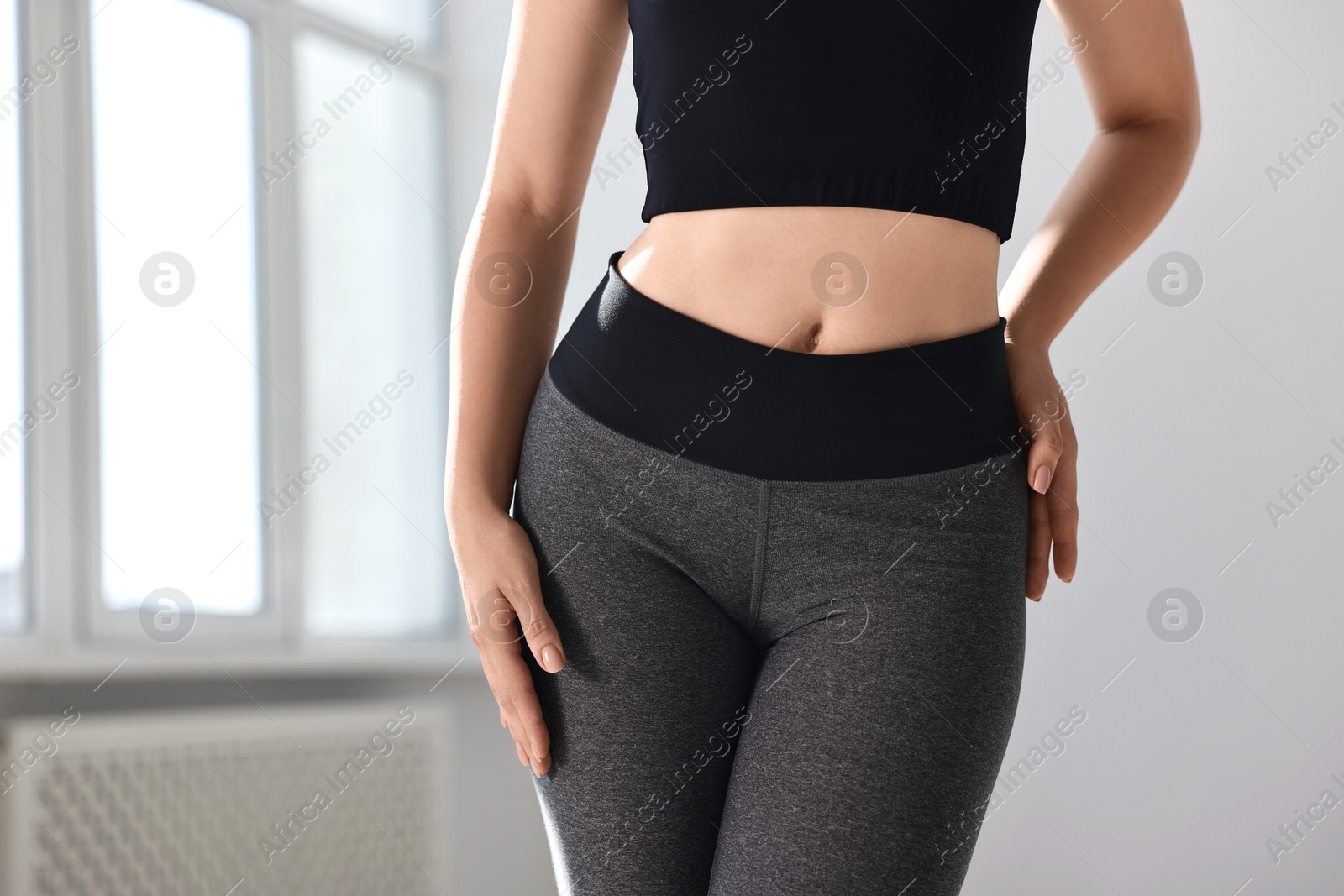 Photo of Woman wearing grey sports leggings indoors, closeup