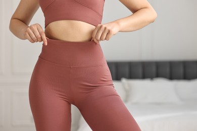 Photo of Woman wearing sports leggings and bra indoors, closeup