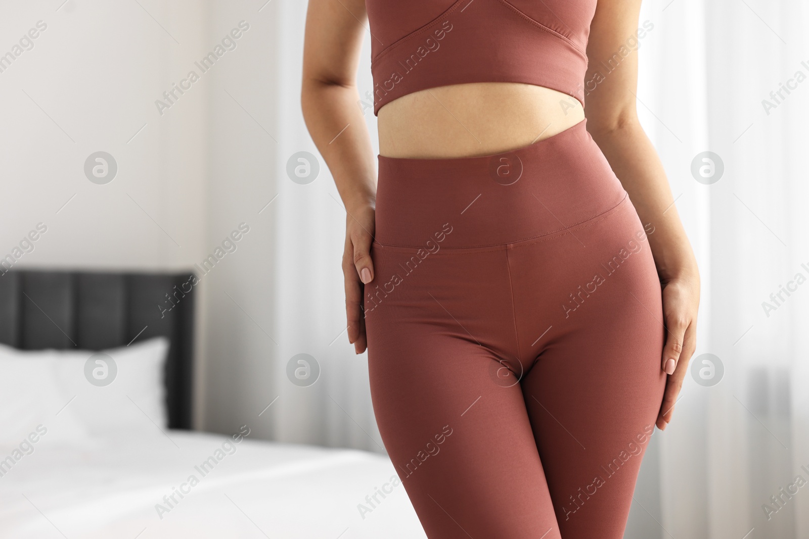 Photo of Woman wearing sports leggings and bra indoors, closeup