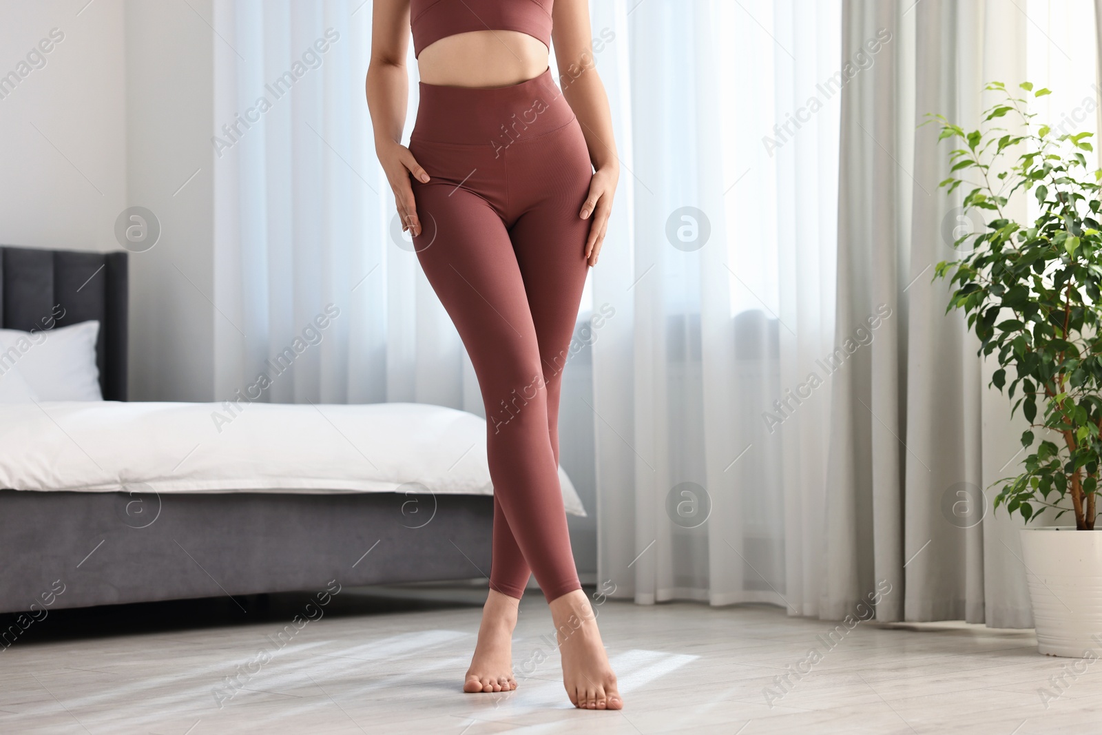 Photo of Woman wearing sports leggings in bedroom, closeup