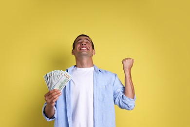 Happy man with money on yellow background