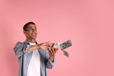 Man throwing money on pink background, space for text