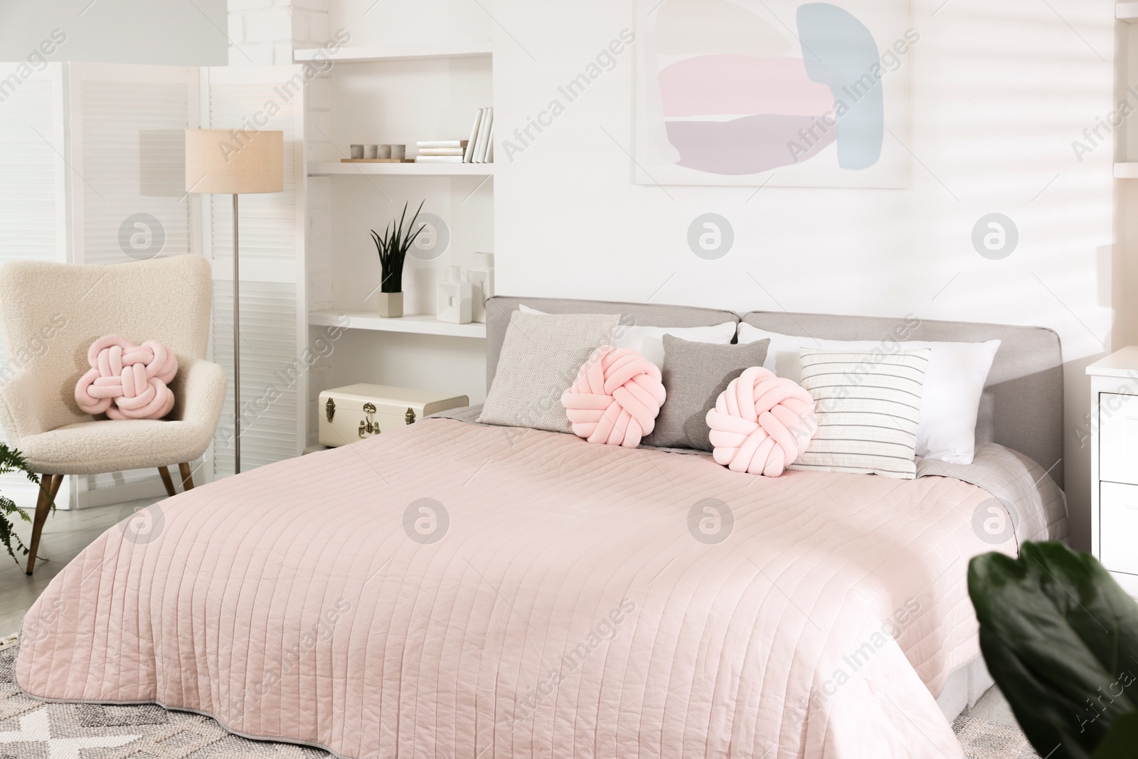 Photo of Large bed with soft pillows in room. Stylish bedroom interior