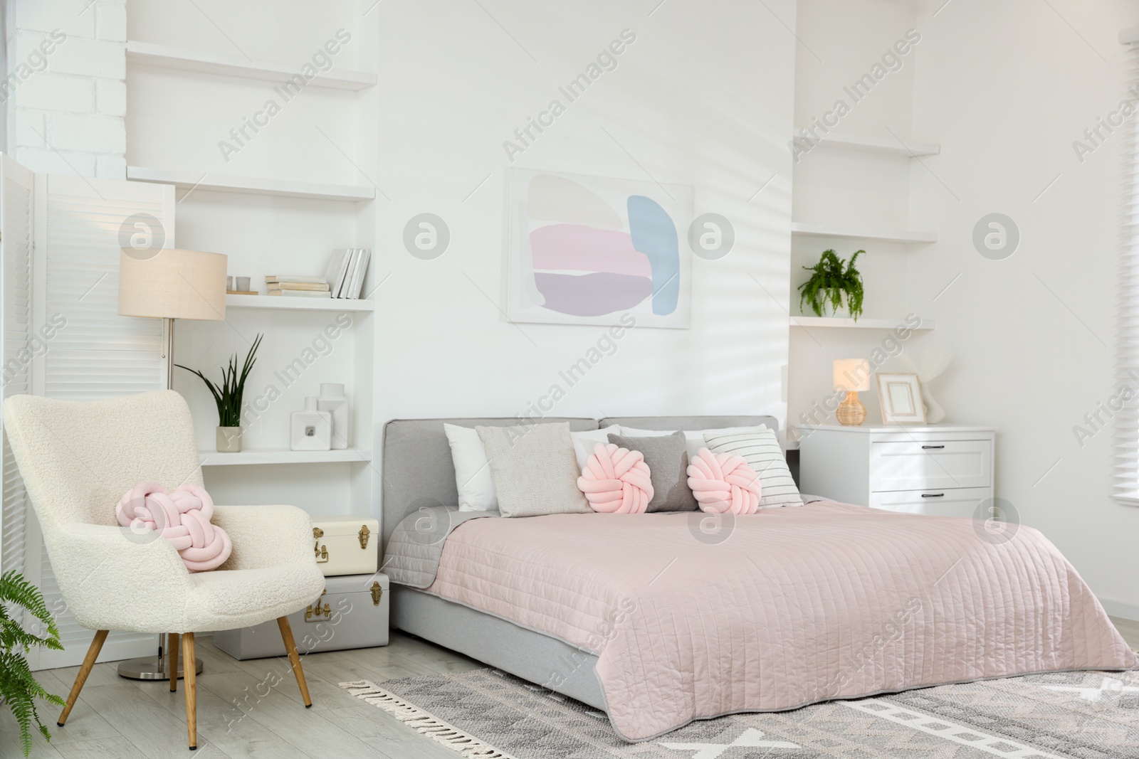 Photo of Large bed, houseplants and decorative elements in room. Stylish bedroom interior