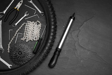 Parts of bicycle and tools on black table, flat lay. Space for text