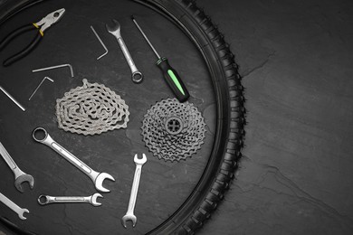 Parts of bicycle and tools on black table, flat lay. Space for text