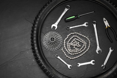 Photo of Parts of bicycle and tools on black table, flat lay. Space for text