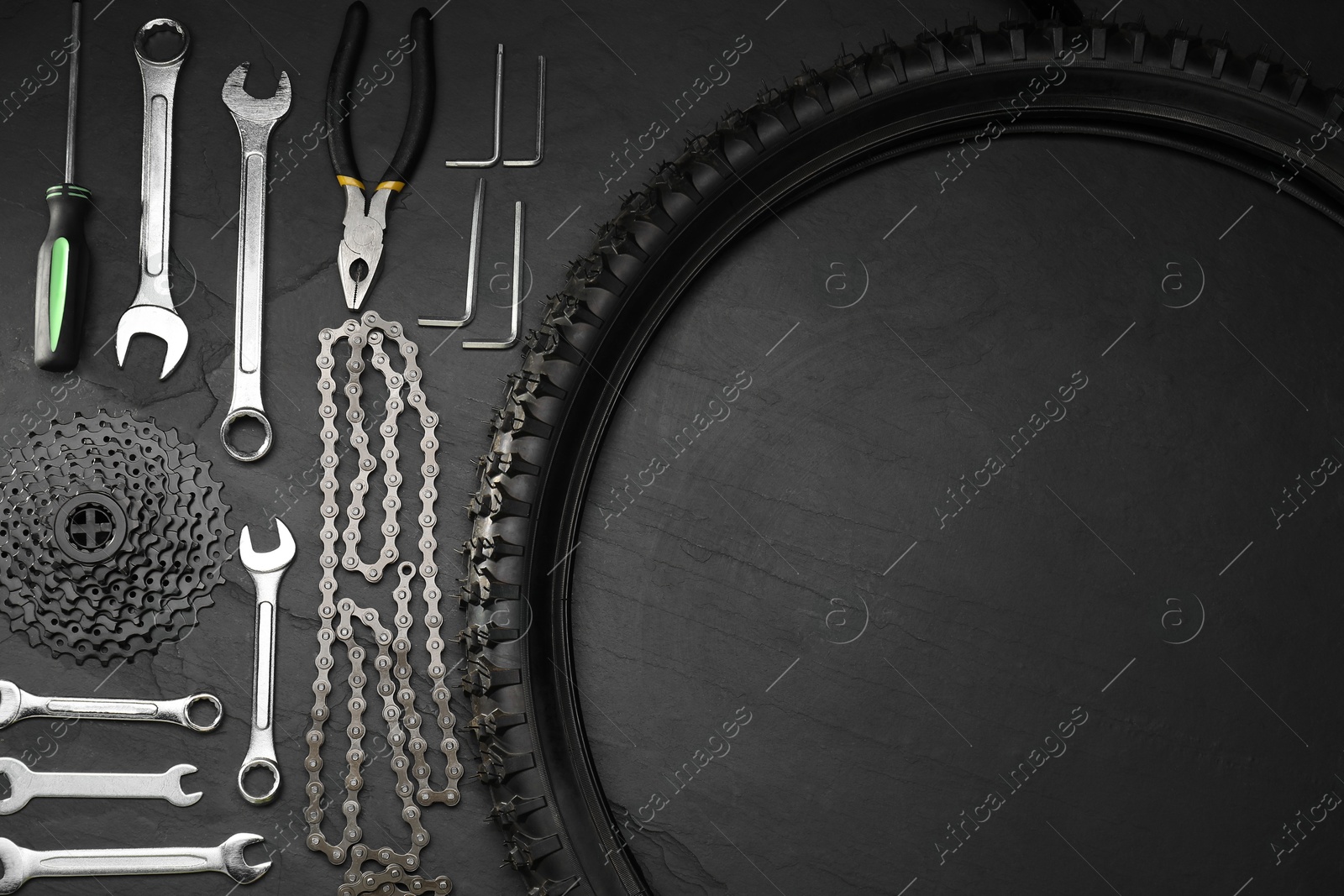 Photo of Parts of bicycle and tools on black table, flat lay. Space for text