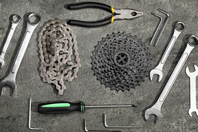 Photo of Parts of bicycle and tools on grey table, flat lay