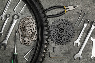 Parts of bicycle and tools on grey table, flat lay