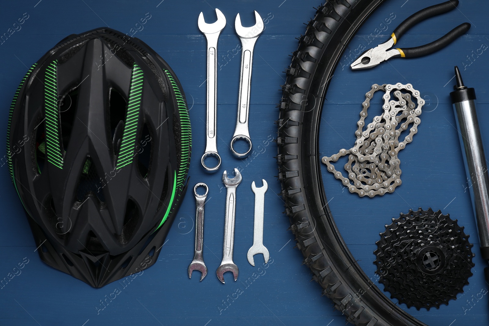 Photo of Parts of bicycle, helmet and tools on blue wooden background, flat lay