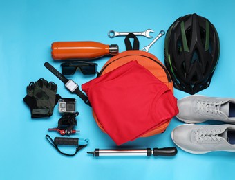 Photo of Bicycle accessories and equipment on light blue background, flat lay