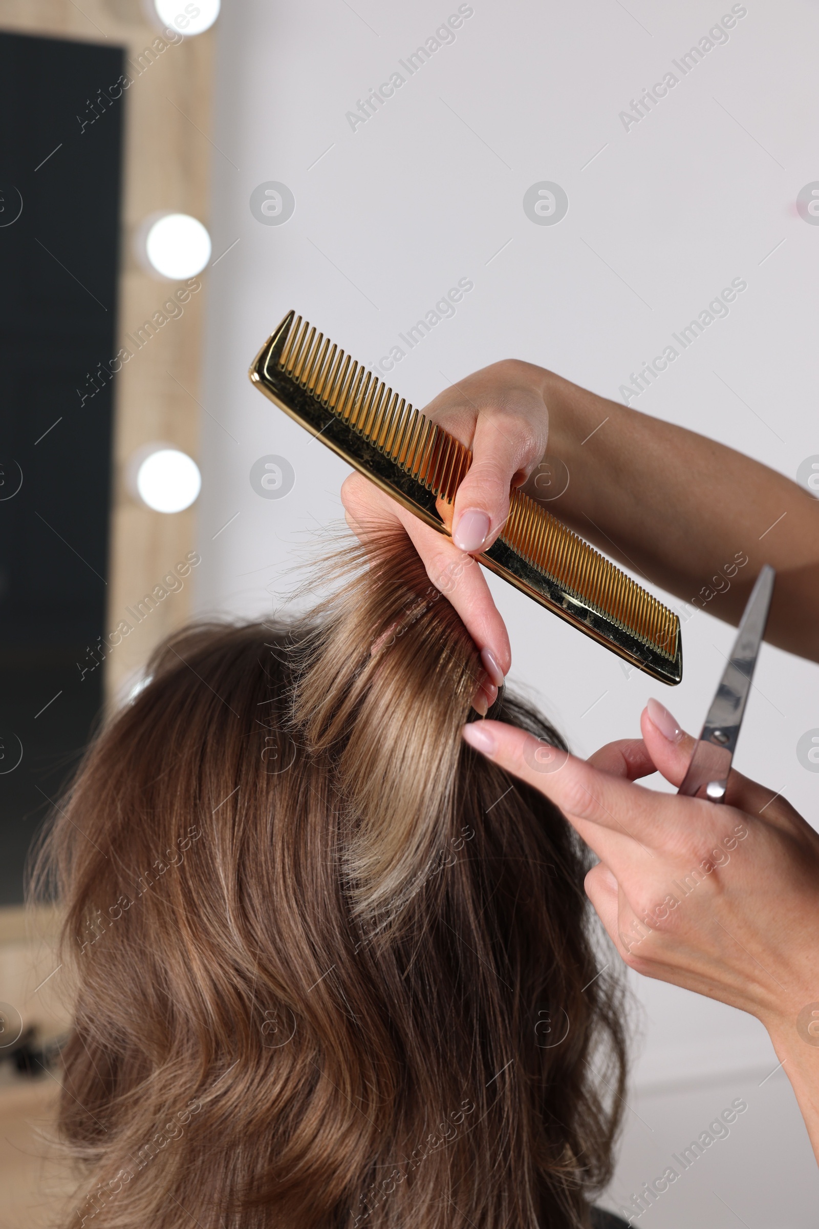 Photo of Hairdresser cutting client's hair with scissors in salon, closeup