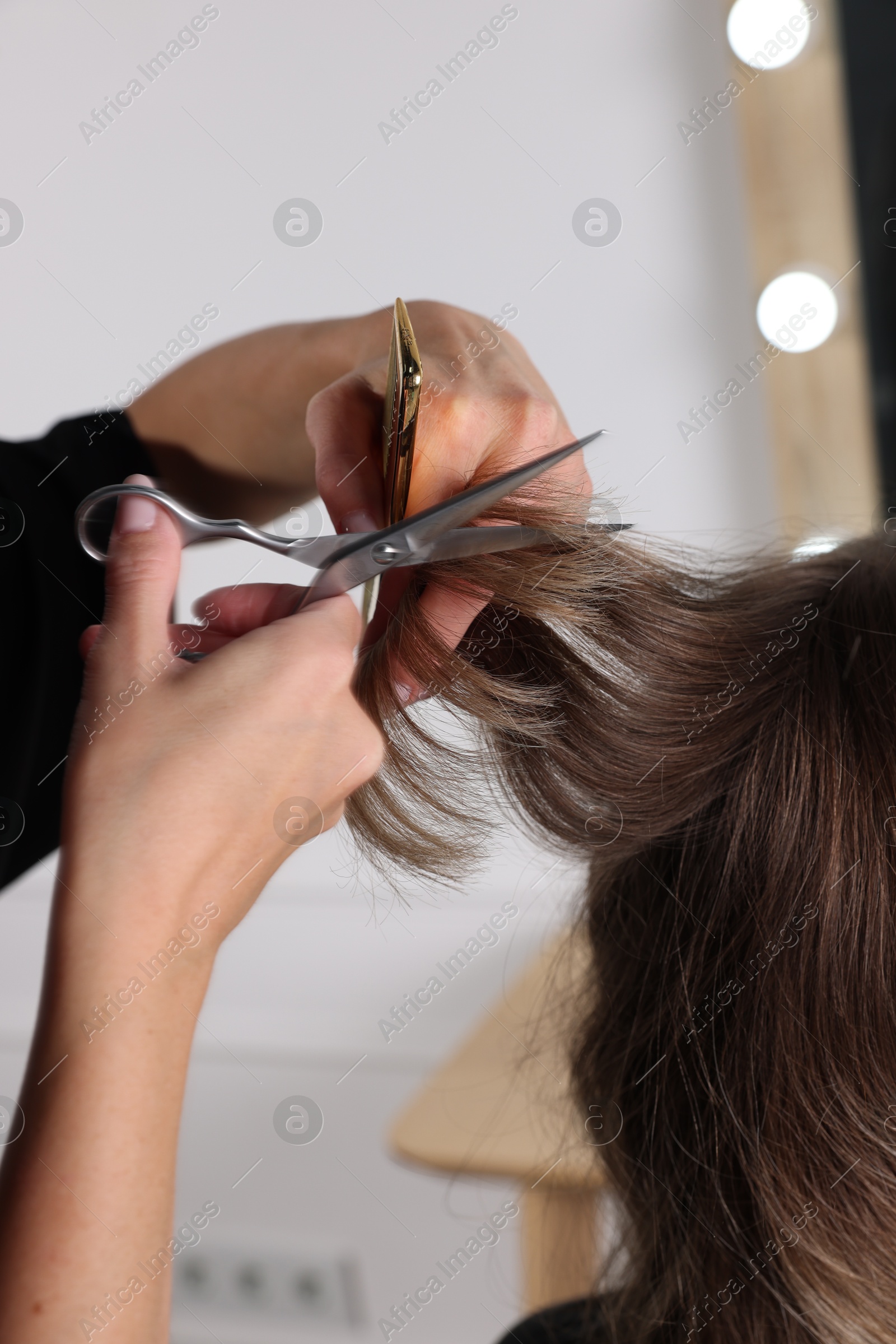 Photo of Hairdresser cutting client's hair with scissors in salon, closeup