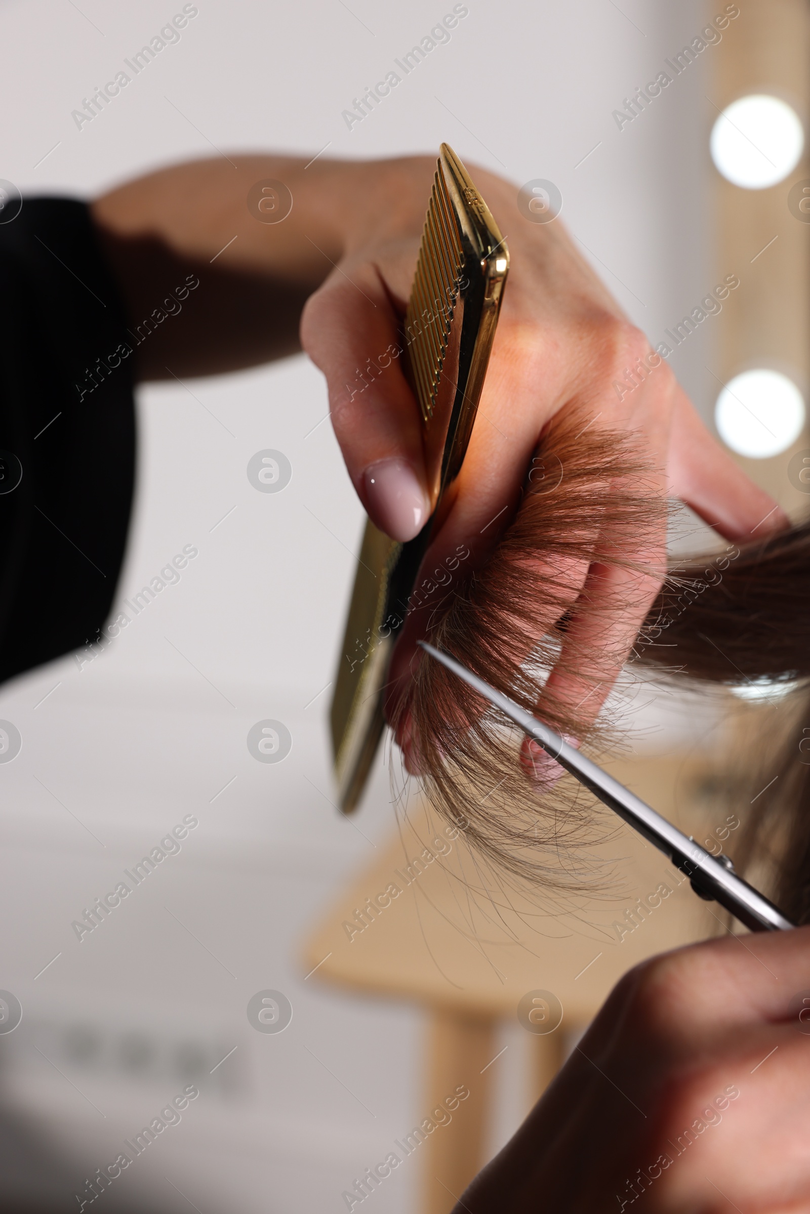 Photo of Hairdresser cutting client's hair with scissors in salon, closeup