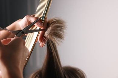 Hairdresser cutting client's hair with scissors in salon, closeup. Space for text