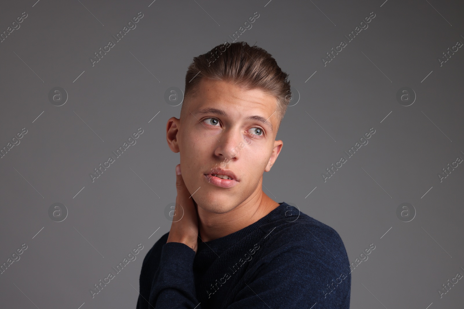 Photo of Handsome young man with stylish haircut on grey background