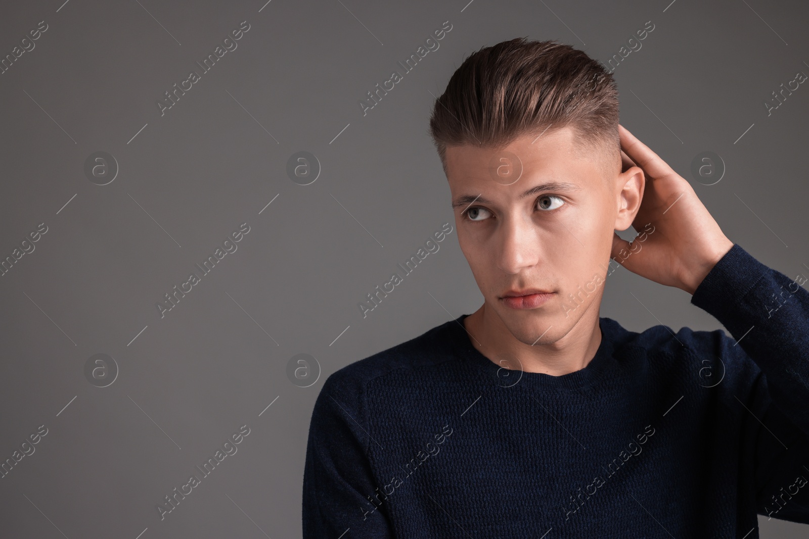 Photo of Handsome young man with stylish haircut on grey background. Space for text