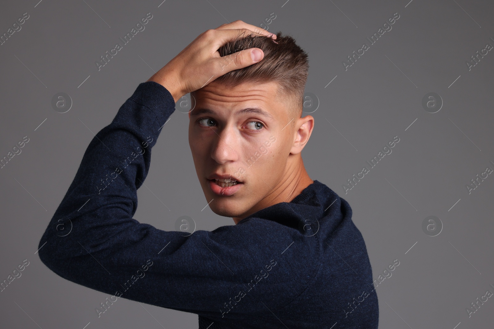 Photo of Handsome young man with stylish haircut on grey background