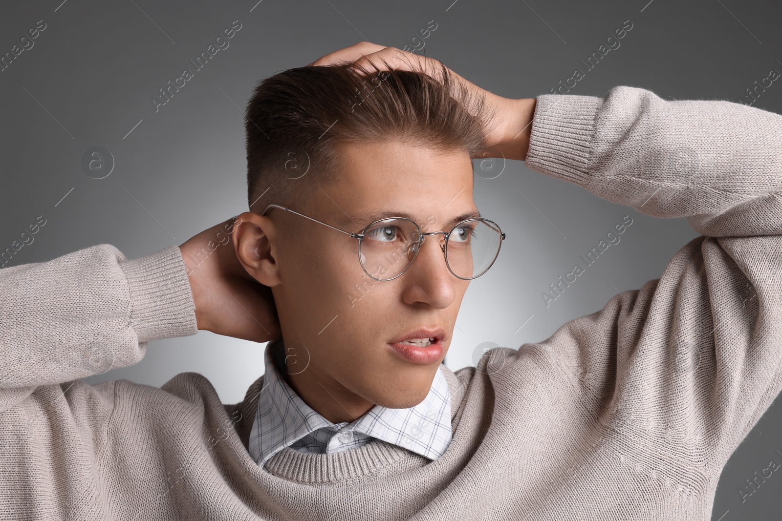 Photo of Handsome young man with stylish haircut on grey background