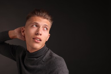 Confident young man with stylish haircut on black background