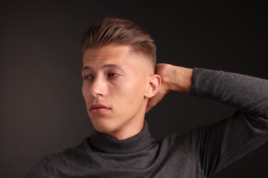 Confident young man with stylish haircut on black background