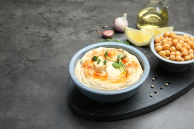 Photo of Delicious hummus with paprika served on dark grey table, space for text