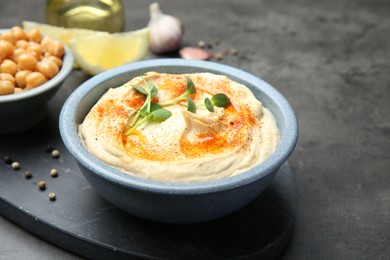 Photo of Delicious hummus with paprika served on dark grey table, space for text