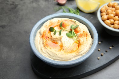 Photo of Delicious hummus with paprika served on dark grey table