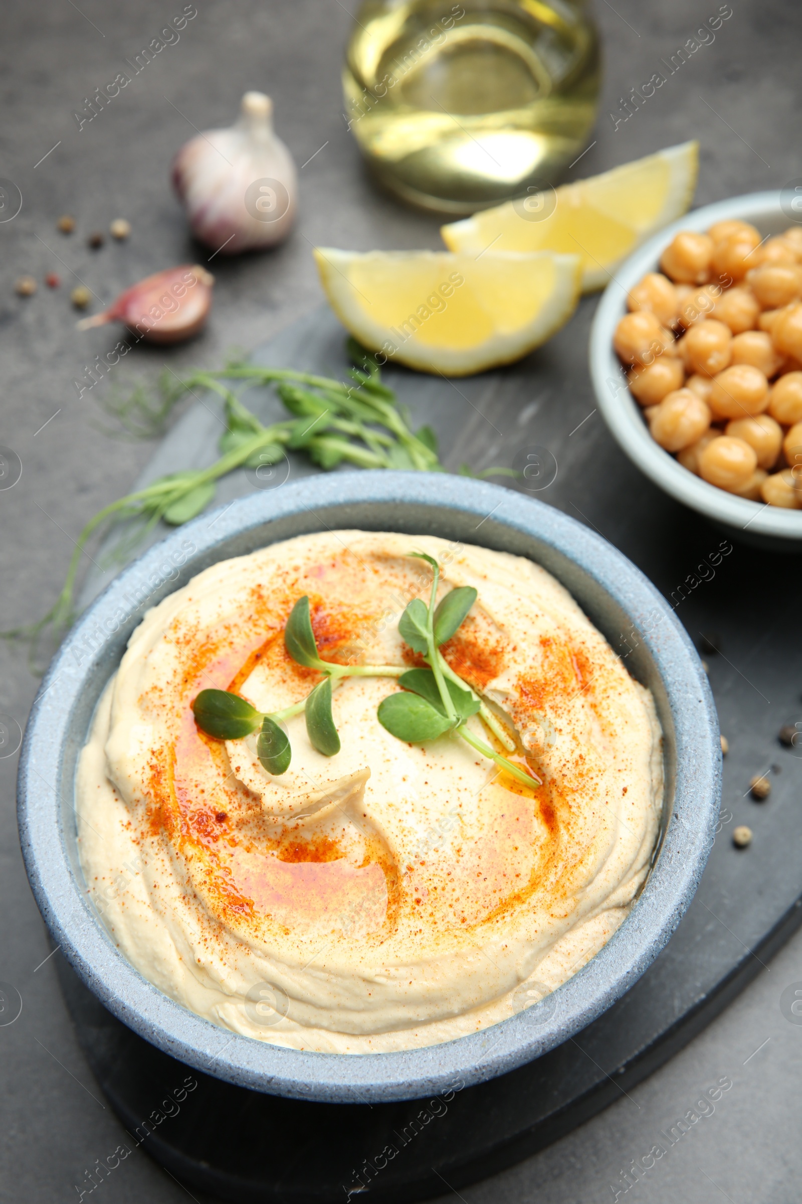 Photo of Delicious hummus with paprika served on dark grey table