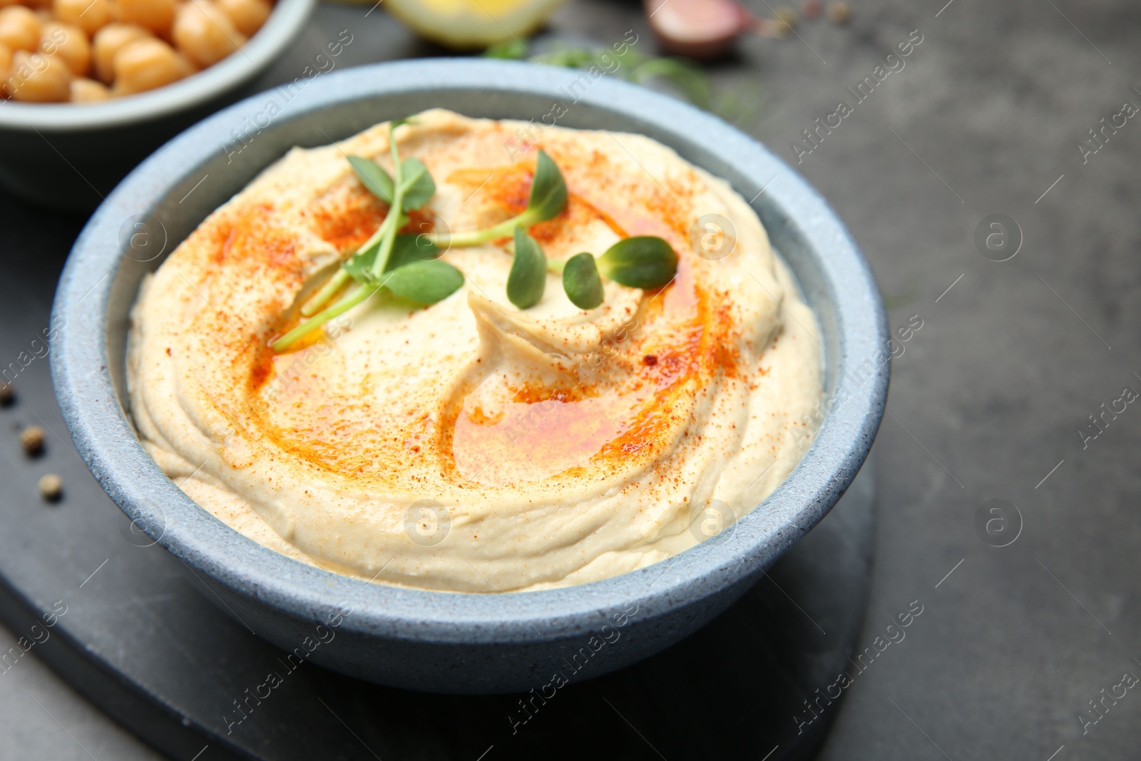 Photo of Delicious hummus with paprika served on dark grey table