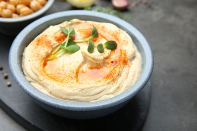 Photo of Delicious hummus with paprika served on dark grey table