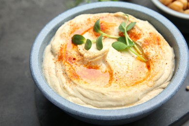 Delicious hummus with paprika served on dark grey table, closeup